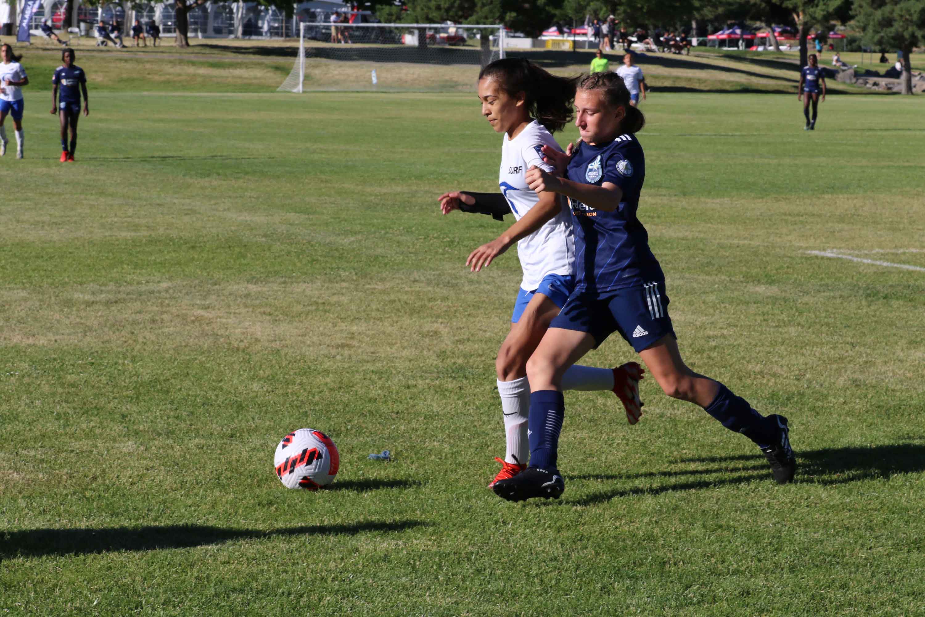 two girls going for the bal tackling each other to win the ball