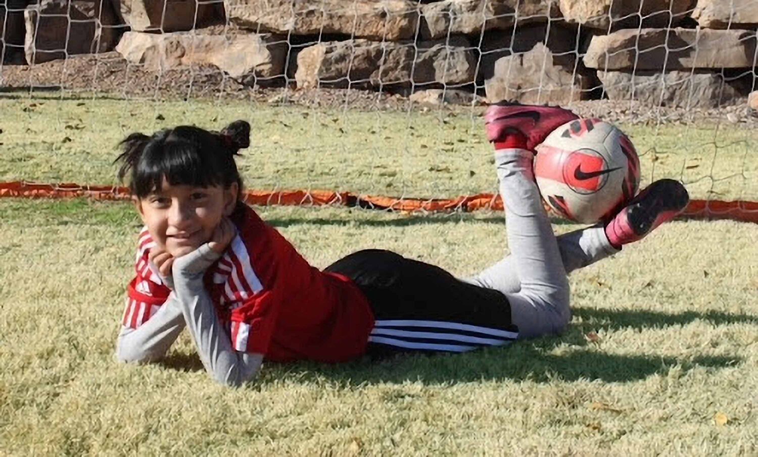 kid laying on the ground holding a ball in between her legs