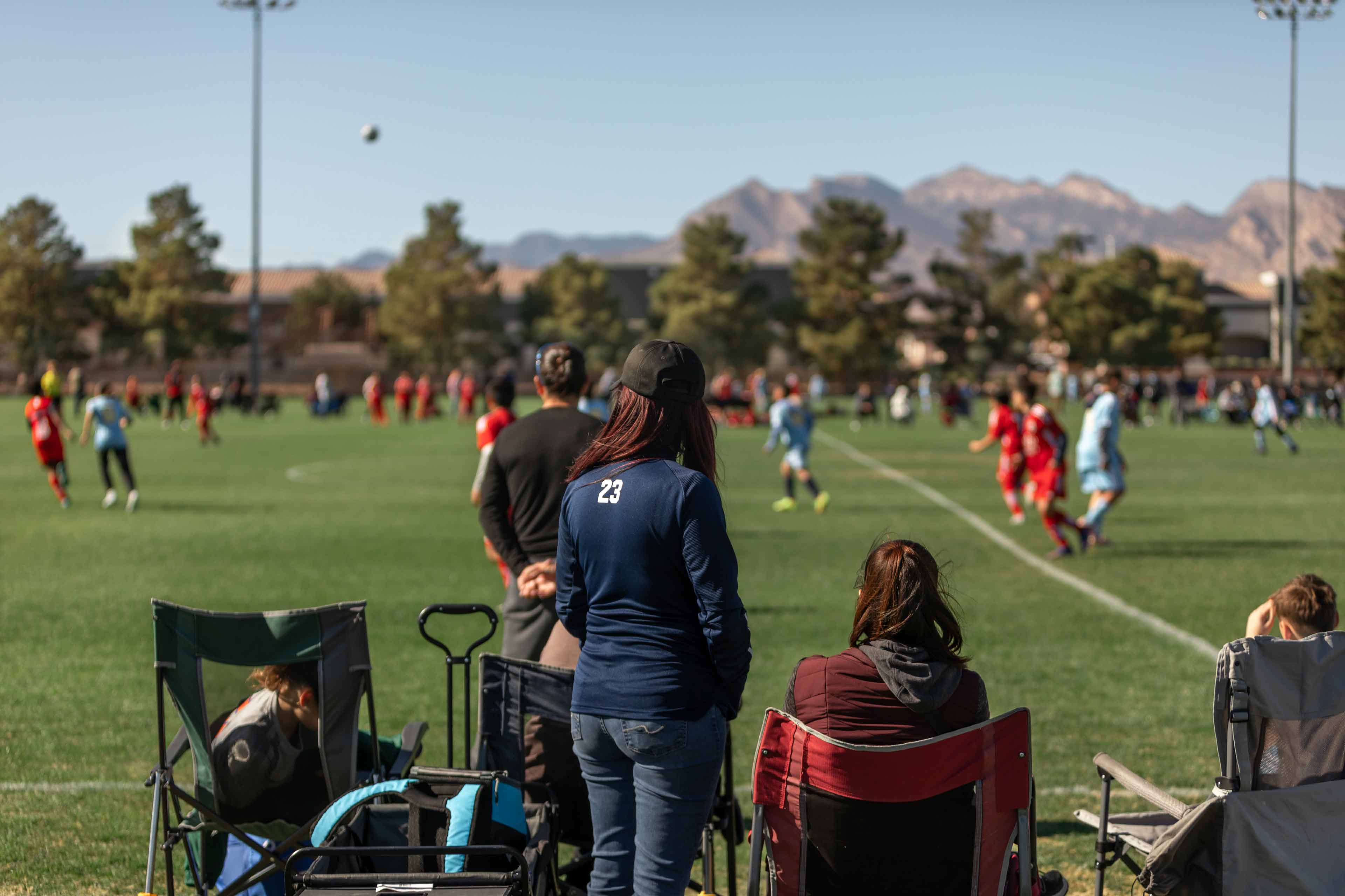 staff sitting on chairs watching a youth socer game