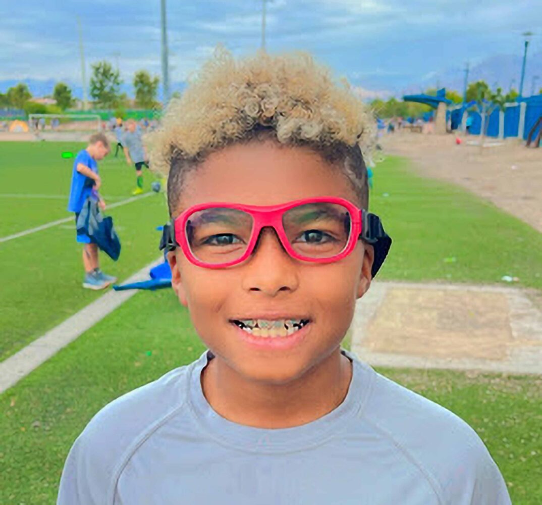 kid with red glasses smiling for a picture