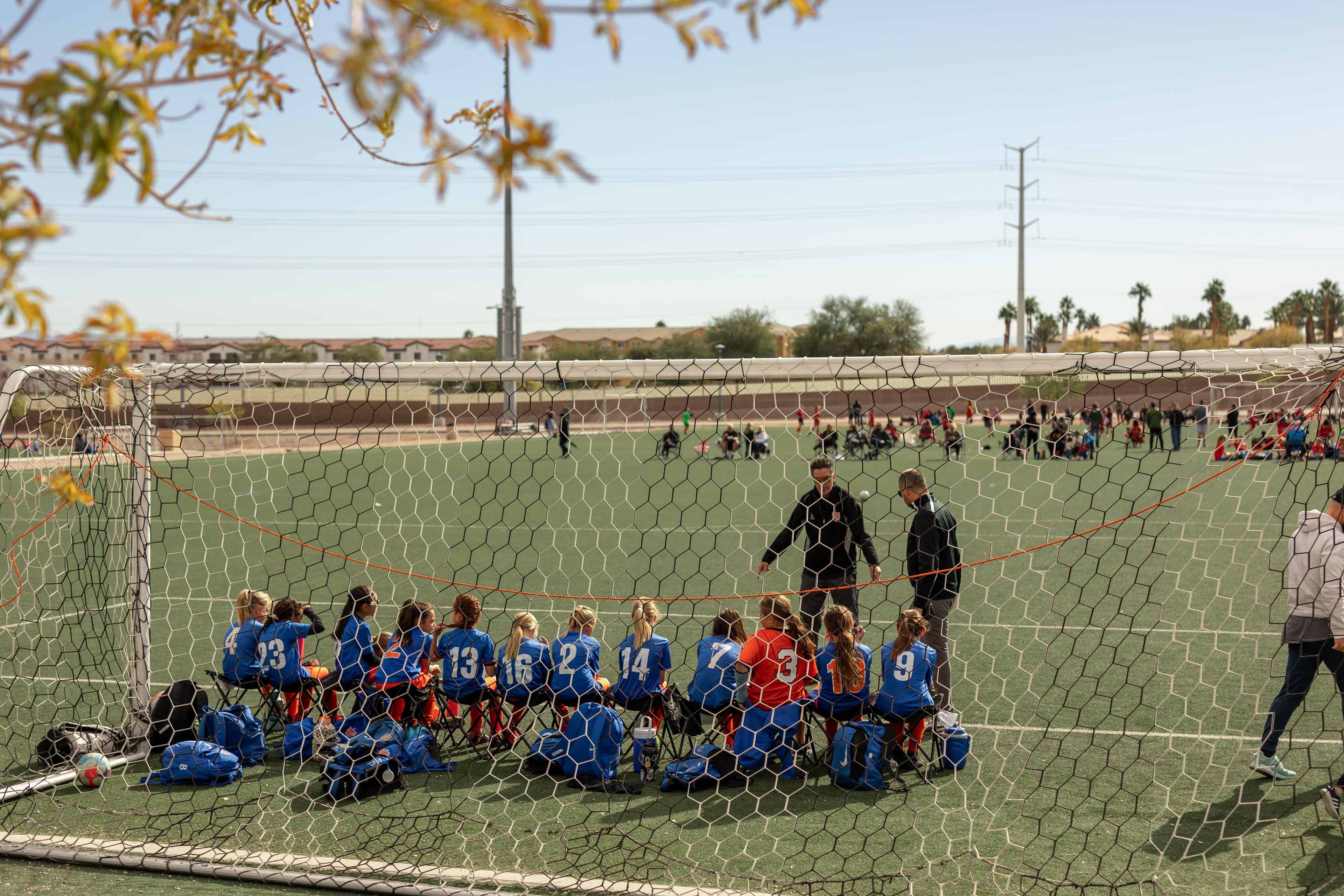 youth soccer team sitting near a goal net